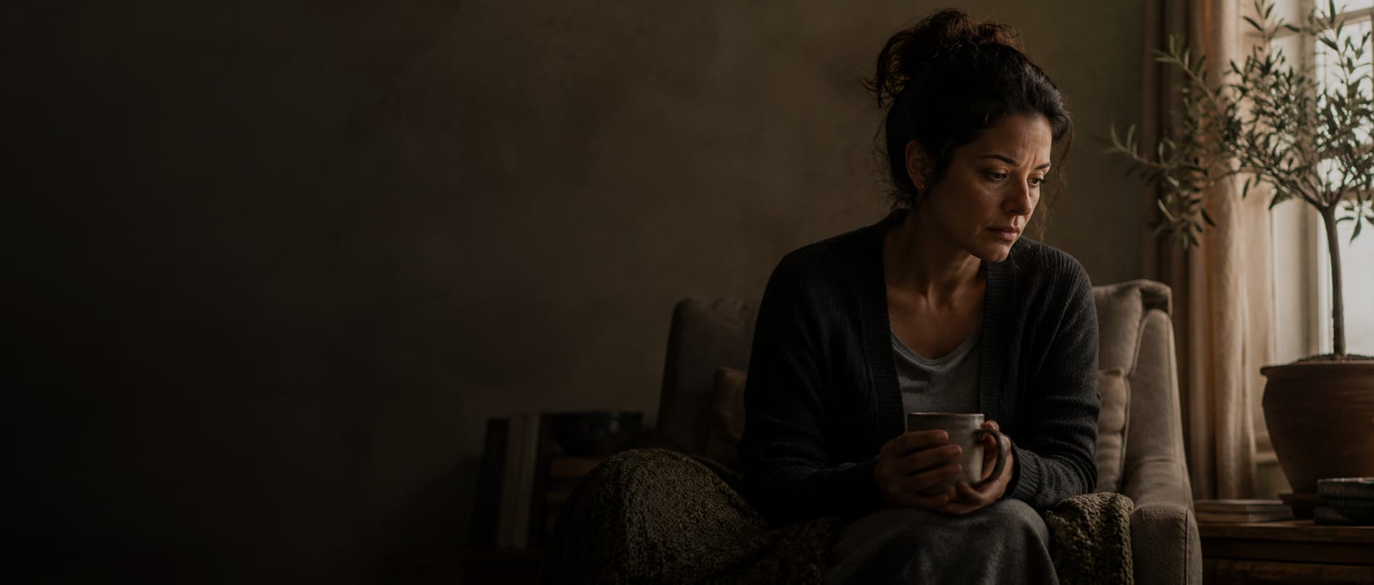 A parent sitting quietly by a window with a cup of coffee